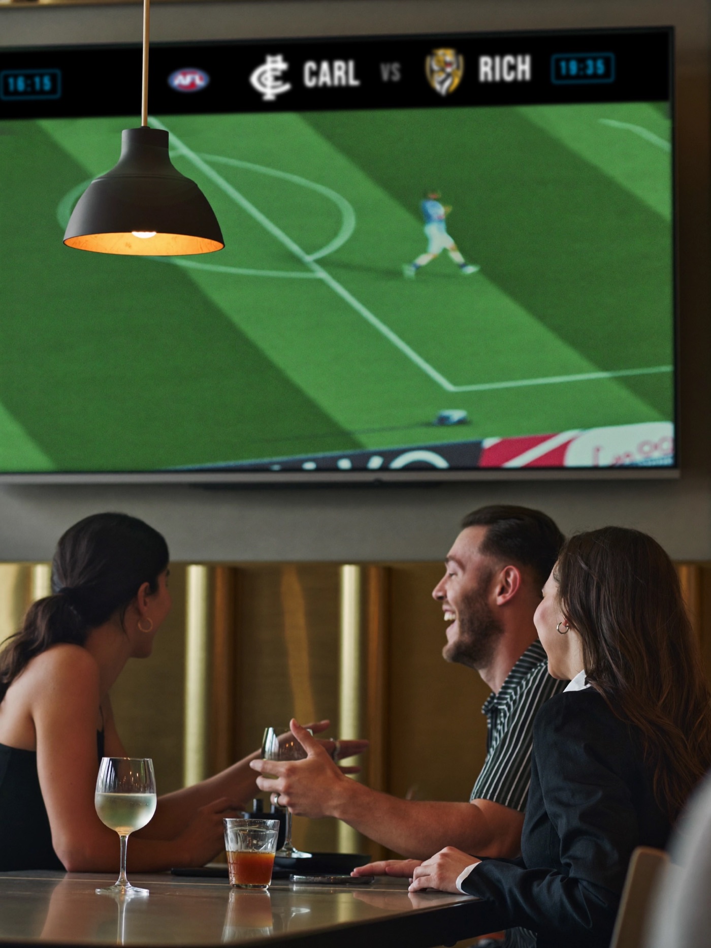 Punters at the bar watching the TV with the Cove Live ticker rolling across the top